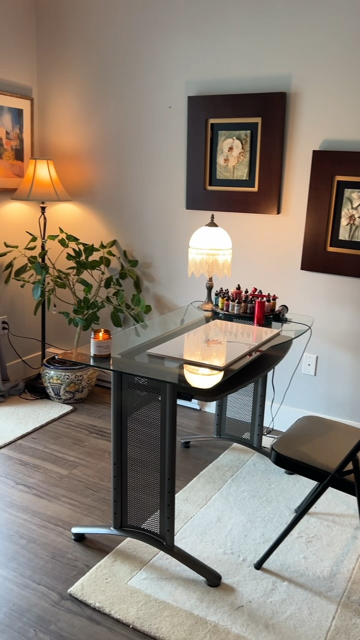 After: The painting desk under framed art, lit by warm lamps