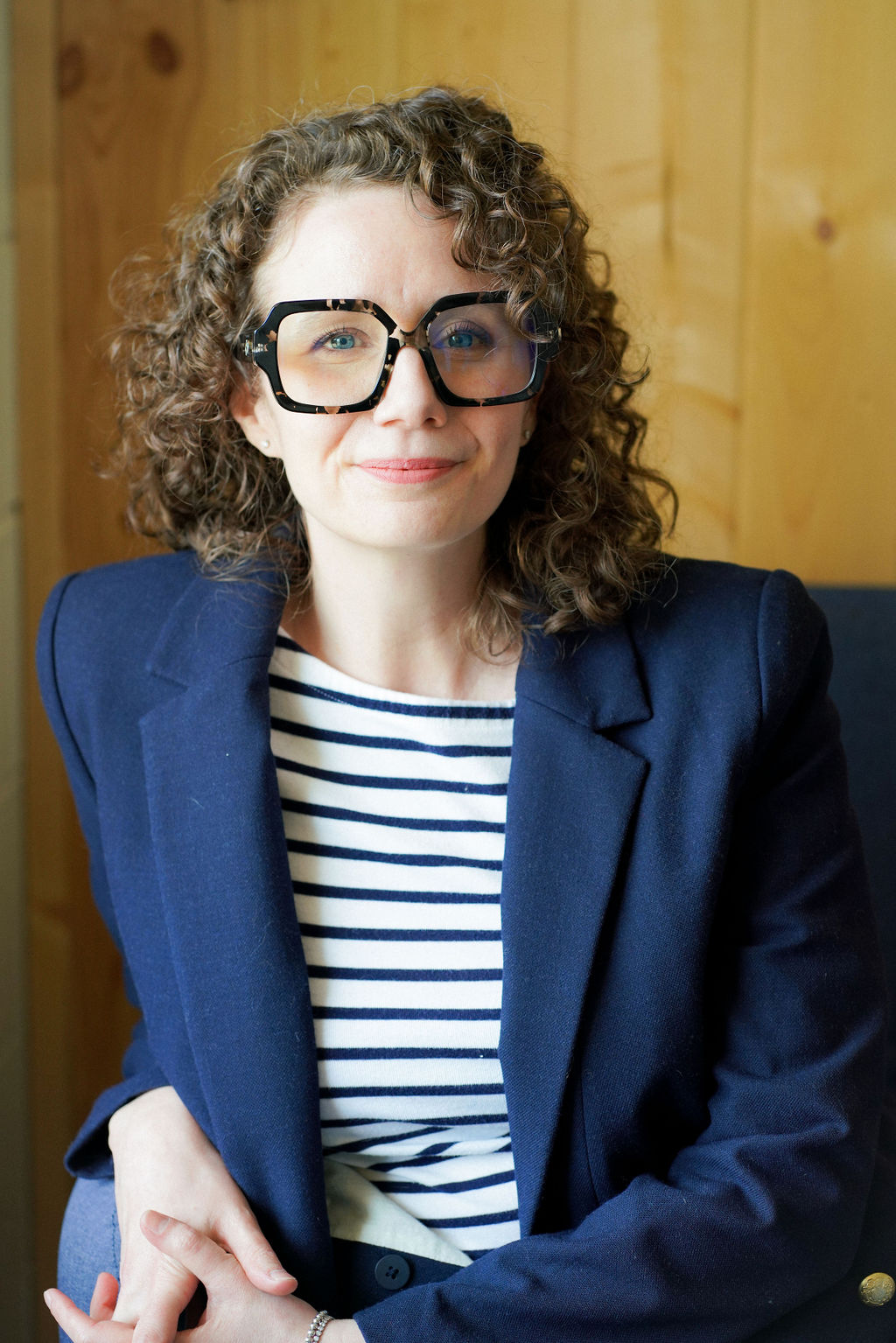 Portrait of Jessie in a navy blazer and striped top, smiling softly